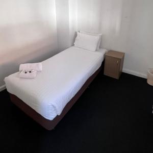 凯阿玛Beachside Budget Rooms的一张白色的床,上面有一条毛巾