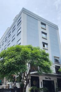 钦奈Hotel Star City的一座高大的白色建筑,前面有一棵树