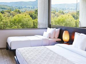 卢特拉基利尼斯Grecotel Ilia Palms & Aqua Park的带大窗户的客房内的两张床