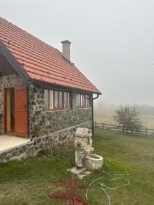 GradacVikendice Šušić的一块石头房子,在田野上有一个红色屋顶
