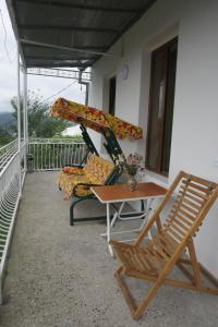 库塔伊西Guest House Nona的阳台配有两把椅子、一张桌子和秋千