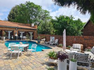 BrakpanRoyal Villa Guesthouse的一个带桌椅的庭院和一个游泳池