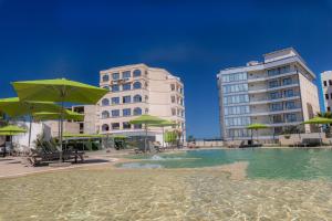 布米尔达斯BOUMERDES PLAZA Hôtel & Spa的一座带绿伞和建筑的水池