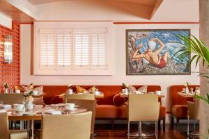 伦敦布卢姆茨伯里酒店的餐厅设有桌子,墙上挂有绘画作品