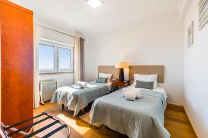 埃里塞拉Ericeira Vista Mar Peace and Sea的客房设有两张床和窗户。