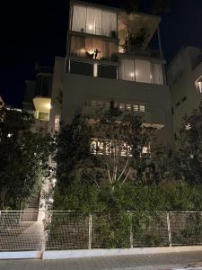 特拉维夫Rothschild 69的一座高大的建筑,晚上有人坐在阳台上