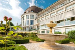不莱梅Parkhotel Bremen – ein Mitglied der Hommage Luxury Hotels Collection的一座花园中的喷泉,位于一座建筑前