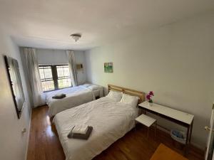 布鲁克林Spacious Bedroom for 4 in shared Townhouse+garden的一间卧室设有两张床、一张桌子和一个窗口。