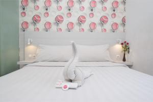 三宝垄Red Orchid Hotel by Sajiwa的一张白色的床,上面有一只动物塞满了东西