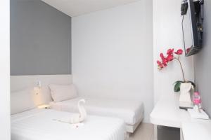 三宝垄Red Orchid Hotel by Sajiwa的白色的房间,设有两张床和一张凳子上的天鹅