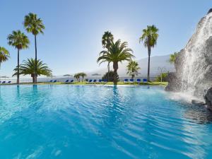 拉克鲁斯Hotel Las Águilas Tenerife, Affiliated by Meliá的一个带瀑布和棕榈树的游泳池
