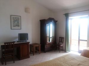 波利卡Agriturismo La Mancosa的一间卧室配有一张床、一台电视和一张书桌