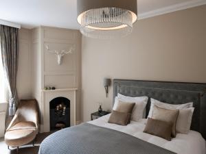温莎Castle Hotel Windsor的一间卧室配有一张床、一把椅子和一个吊灯。