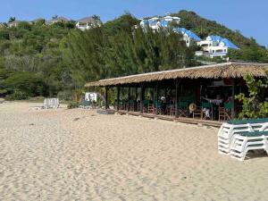 圣马丁岛Friar's beach - Luxurious unit by the beach的海滩上设有小屋,上面摆放着桌椅