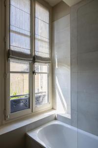 圣艾米隆Hotel Porte Brunet的带浴缸的浴室和窗户。
