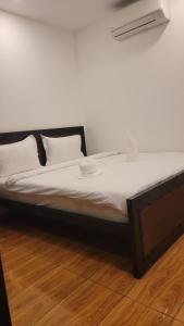 贡布Park Inn Boutique and Hostel的铺有木地板的一张带白色床单和枕头的床