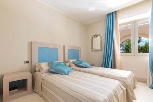 托雷拉皮罗Villa Bianca by Perle di Puglia的一间卧室配有两张带蓝色枕头的床