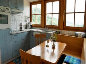 HorbenFerienwohnungen Ringlihof的一间带木桌的厨房和一间带蓝色橱柜的厨房