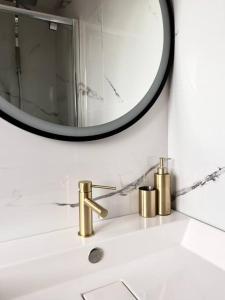 维勒班LE PUNTA CANA的浴室水槽设有镜子和金色水龙头