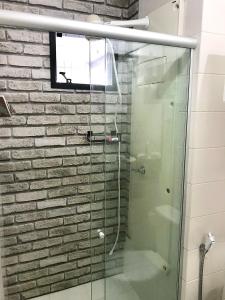 贝伦Mobiliado e aconchegante的砖墙浴室内的玻璃淋浴间