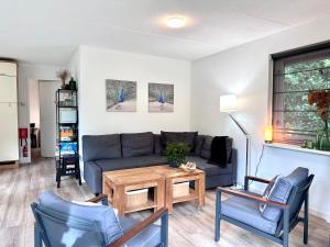 伊皮Vakantiehuis Bos en Hei Veluwe的客厅配有沙发、椅子和桌子