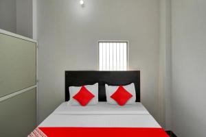 MurādnagarOYO Flagship Amazing Inn的一张带红色和白色枕头的床
