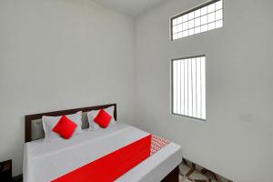 MurādnagarOYO Flagship Amazing Inn的一间卧室配有一张带红色枕头的床和一扇窗户