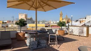 塞维利亚Joya del Casco Boutique Hotel by Shiadu的屋顶上带桌子和遮阳伞的天井
