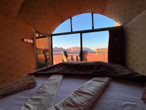 瓦迪拉姆贝都因人时尚露营旅馆的一张位于带大窗户的房间内的床铺