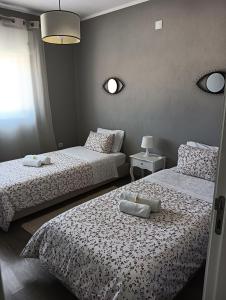 圣若昂达佩什凯拉House da Didy的一间卧室设有两张带白色床单的床和窗户。