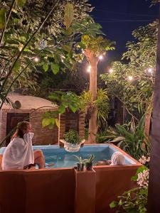 危地马拉安地瓜RUAJ HOSTAL -Wellness-Colonial-Exclusive-的女人晚上坐在花园里的热水浴缸里