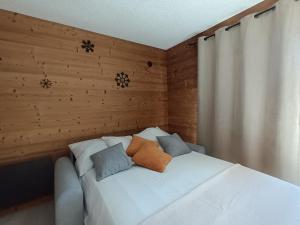 圣米舍德谢洛Appartement montagne LE FLOCON的木墙客房内的一张白色床