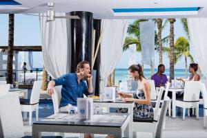 蒙特哥贝Riu Palace Jamaica - Adults Only - All Inclusive Elite Club的坐在海滩上餐厅桌子上的男女