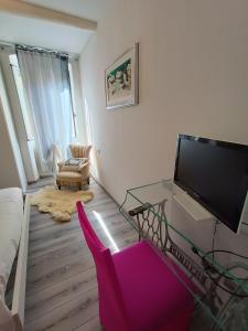 普拉托La Casina Pallacorda的客厅配有电视和粉红色椅子