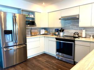 BowserThe Beach House at Deep Bay的厨房配有白色橱柜和不锈钢冰箱