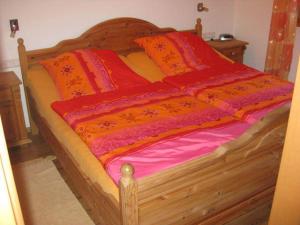 SachrangFerienhaus Sachrang的一张带橙色和红色床单的木床和枕头