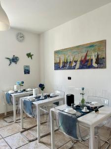 安科纳B&B Il Poeta sul Mare的一间设有桌椅的房间和墙上的绘画