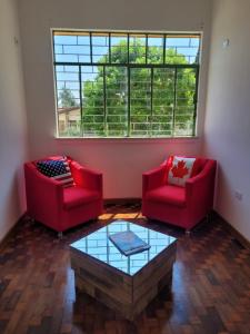库里提巴Hostel Kaizen的客厅配有2把红色椅子和咖啡桌