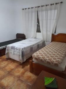 瓜鲁雅Aconchego的一间卧室设有两张床,窗户配有窗帘