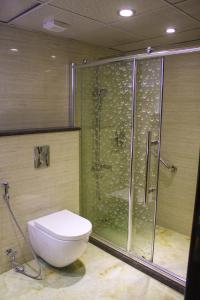 安曼Qaser Al-Sultan Hotel Suites的带淋浴、卫生间和玻璃淋浴间的浴室