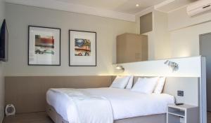 圣地亚哥Novapark的卧室配有一张白色大床,墙上挂有三张照片