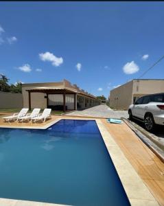 圣阿马鲁Dunas residence casa 03的一座带两把椅子的游泳池以及一座建筑