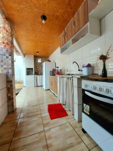 杰里科科拉Na Casa Delas Jeri - com Churrasqueira的厨房配有白色家电和红色地毯。
