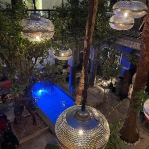 马拉喀什Riad des Mile Nuits的后院的游泳池,有灯光和树木