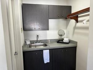 阿尔伯克基Desert Sands Inn & Suites的一个带水槽和镜子的小厨房