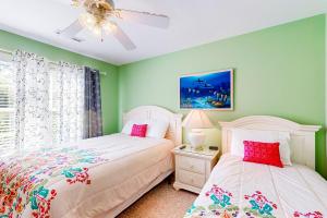 默特尔比奇The Singing Gull的卧室设有两张床铺、绿色墙壁和吊扇