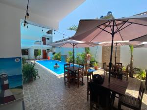 曼克拉Hospedaje Ola Marina的房屋旁带桌子和遮阳伞的游泳池
