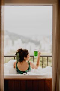 布卢梅瑙Villa do Vale Boutique Hotel的躺在床上喝一杯绿饮料的女人