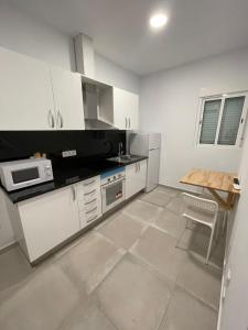 巴塞罗那La Meridian II的厨房配有白色橱柜和桌子