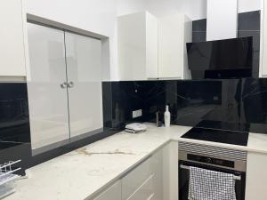巴塞罗那La Meridian II的厨房配有白色橱柜和黑色瓷砖